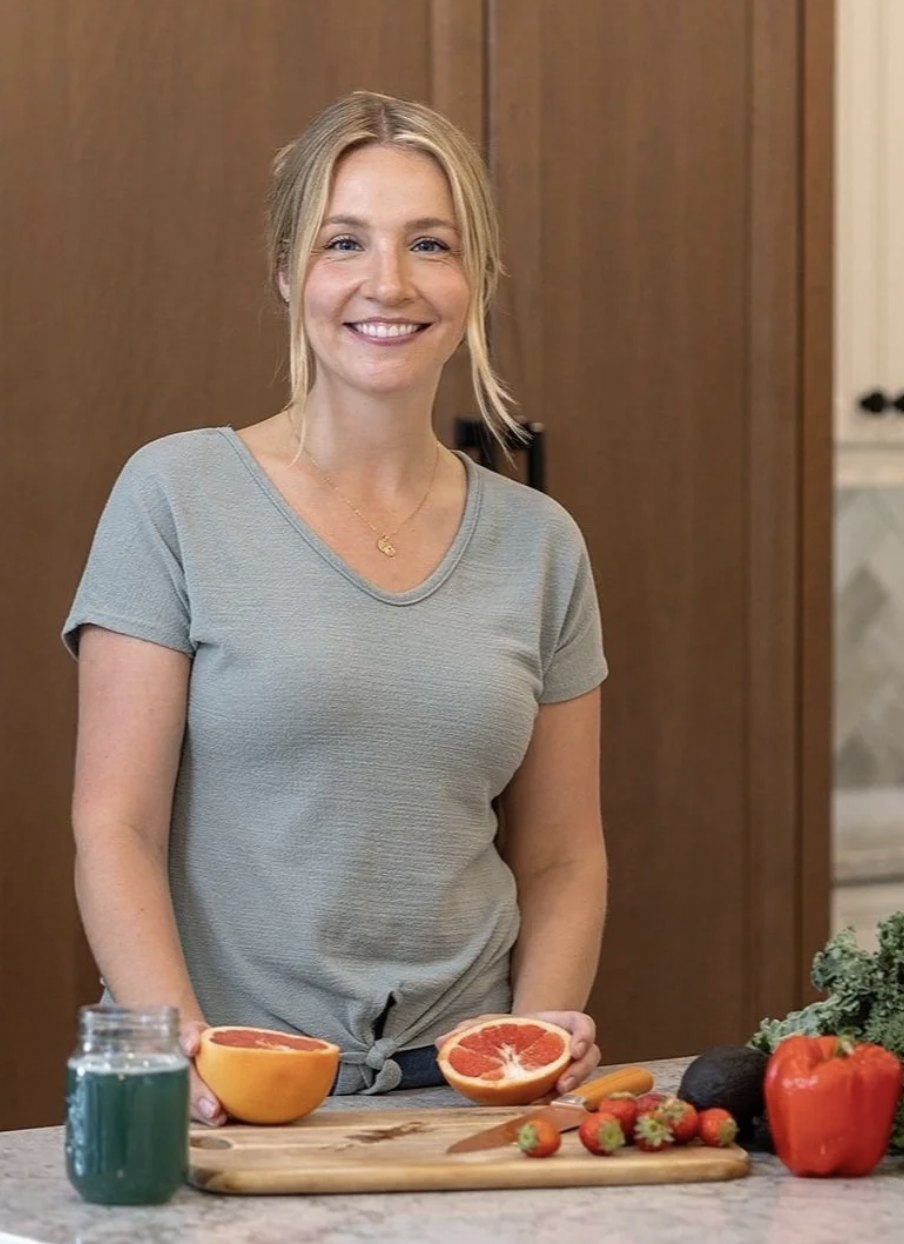 Allysa in her kitchen with grapefruit, strawberries and fresh vegetables